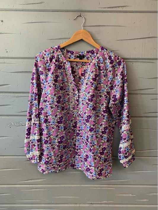 Long-sleeve floral blouse in purple, pink, and white with a V-neck and gathered cuffs.