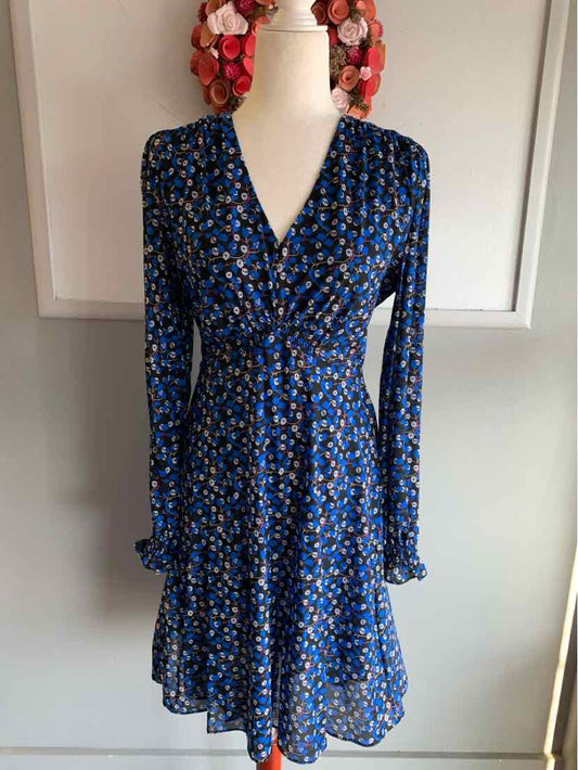 Blue floral long-sleeve wrap dress with V-neck and ruffled hem on mannequin.