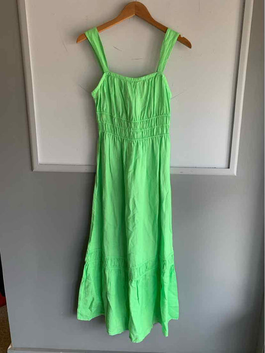 Light green sleeveless maxi dress with gathered bodice and wide shoulder straps hanging on wooden hanger.