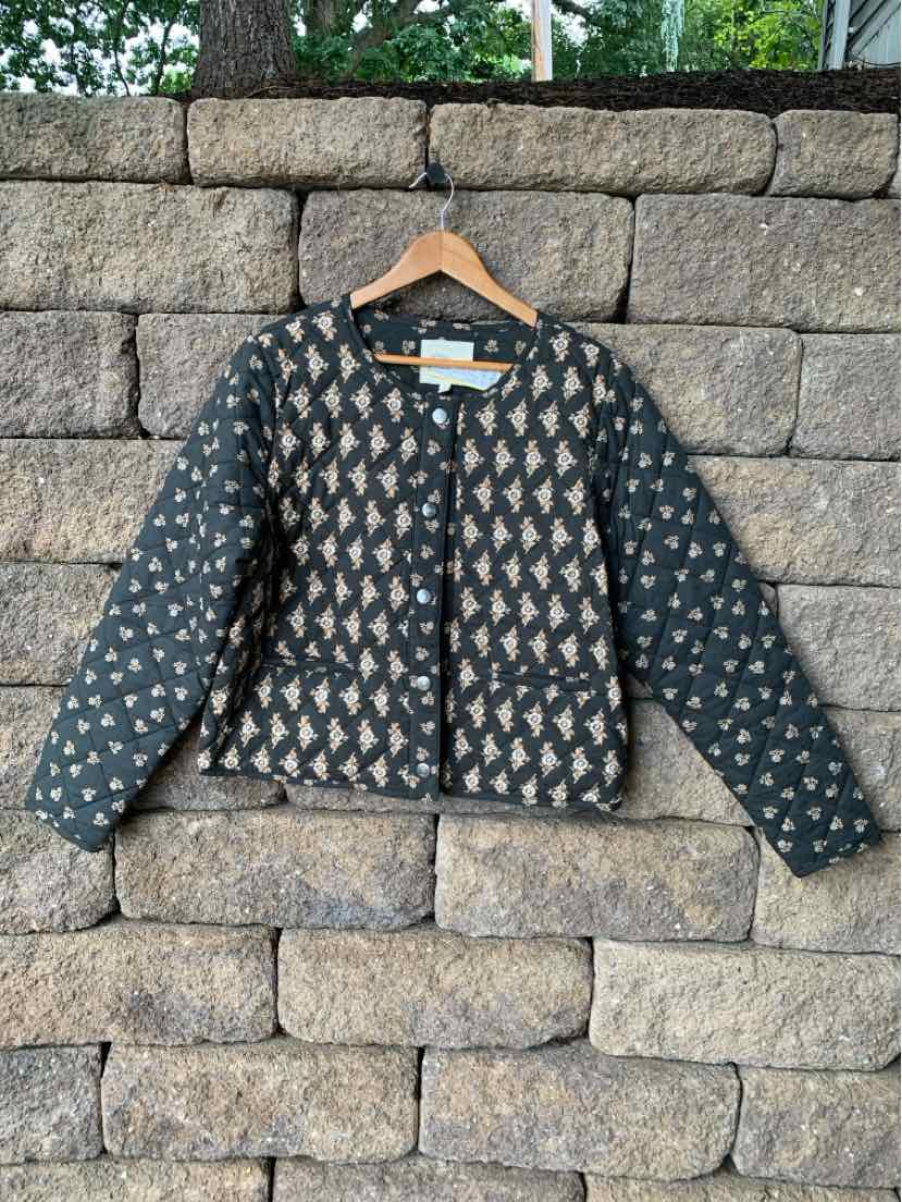 Gray quilted jacket with geometric pattern, round neckline, long sleeves, and zipper front closure.
