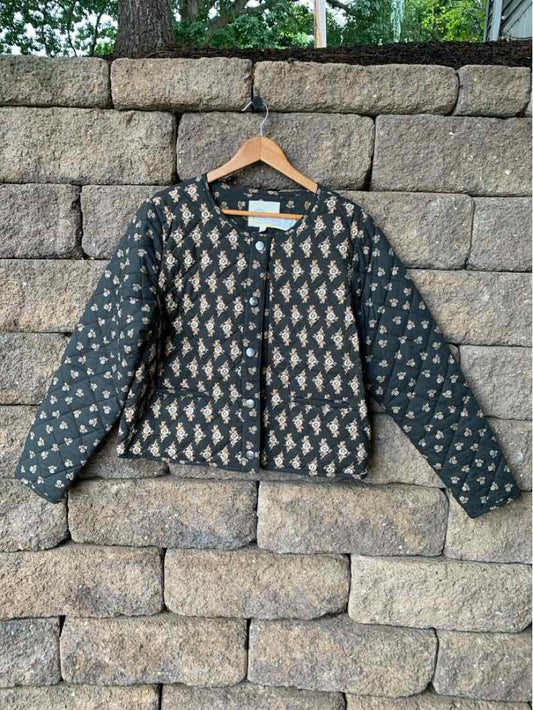 Gray quilted jacket with geometric pattern, round neckline, long sleeves, and zipper front closure.