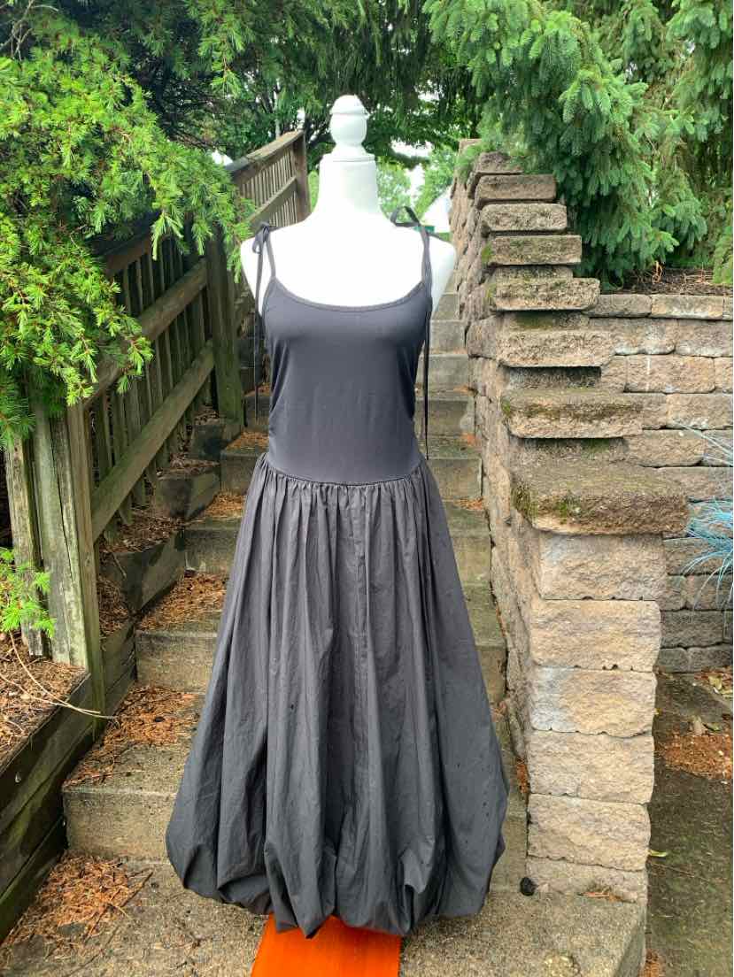 Black sleeveless dress with fitted bodice and full balloon hem, midi length.