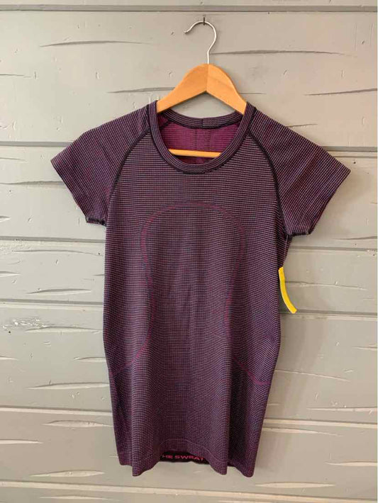 Purple short-sleeve athletic top with crew neck and fitted silhouette on wooden hanger.