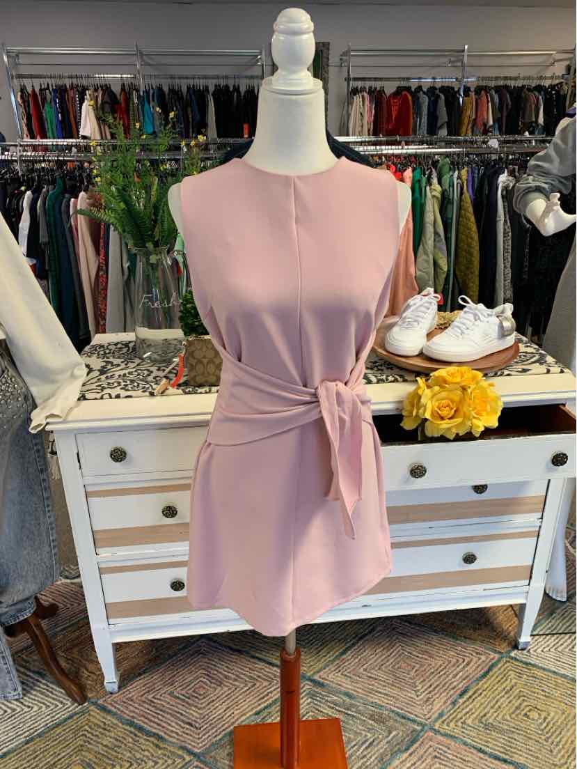 Sleeveless pink wrap dress with side tie detail on mannequin in boutique setting.