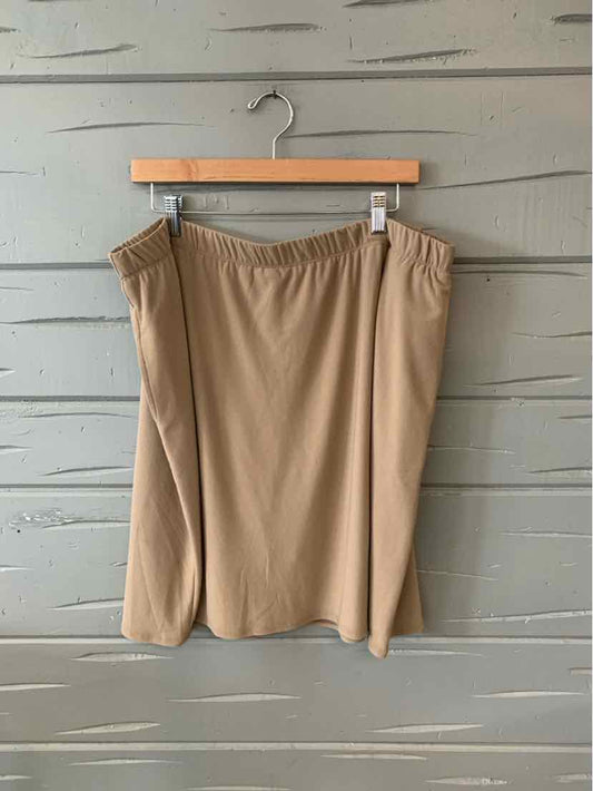 Beige knee-length skort with elastic waistband hanging on wooden hanger against gray wood panel background.
