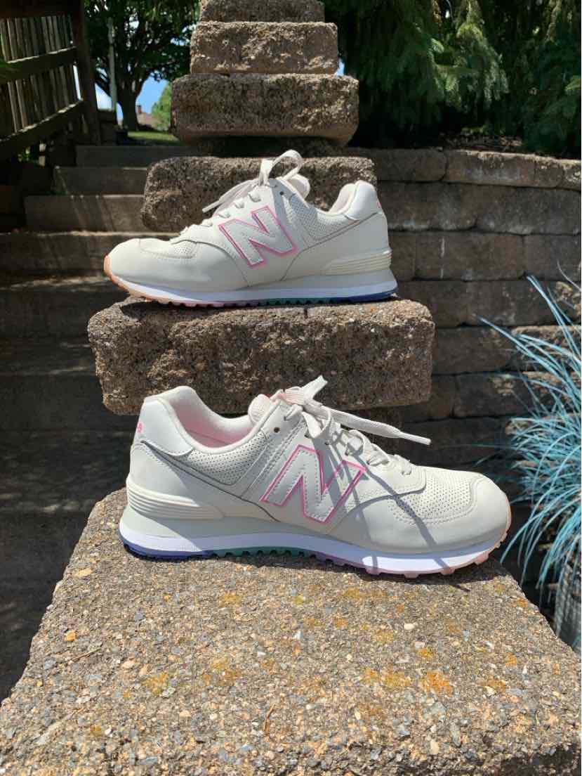 Woman's New Balance sneaker in light gray with pink "N" logo, suede and mesh upper, white sole, size 9.