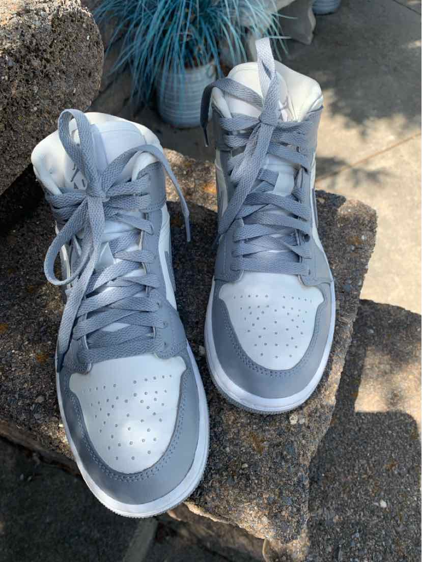 Light gray and white high-top Nike sneakers with perforated toe box, laces, and padded ankle collar.