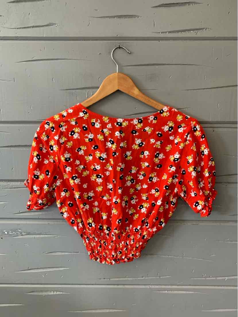 Red cropped blouse with white and black floral print, puff sleeves, and elasticated waist and cuffs.
