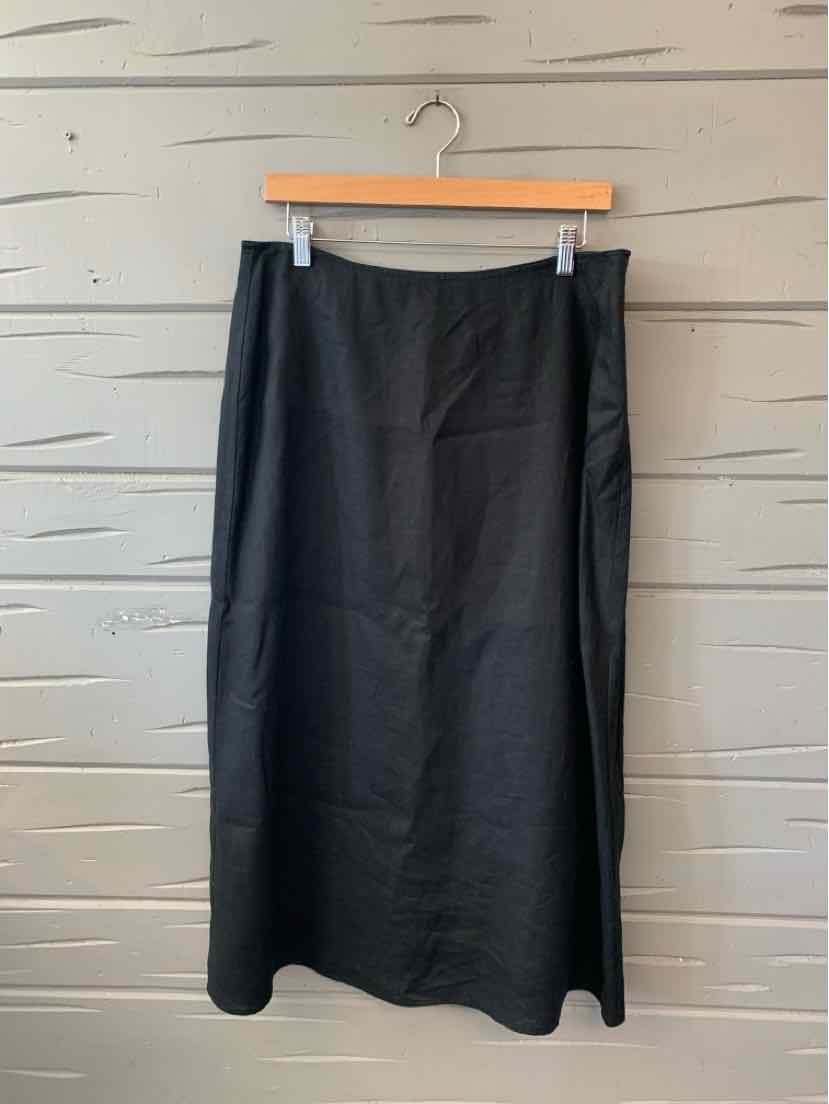 Black midi skirt with slight flare at hem, smooth fabric, size 10, hanging on wooden hanger.
