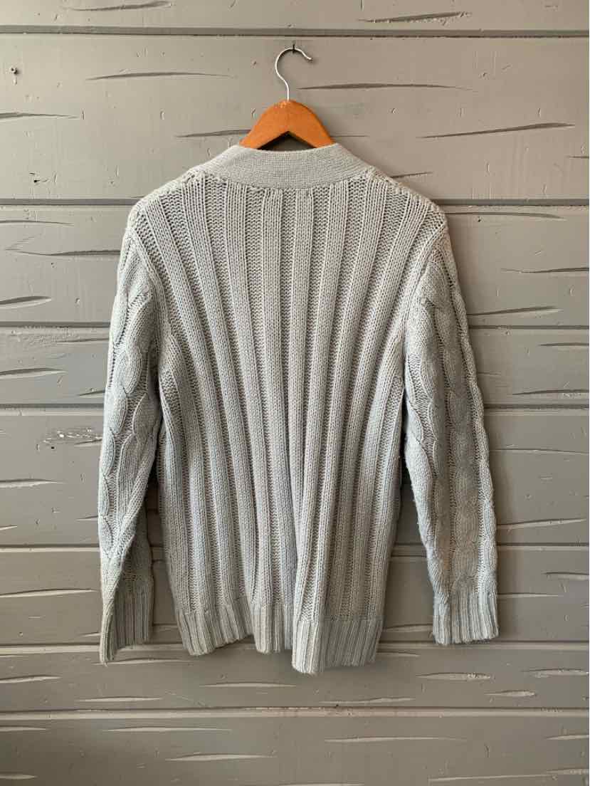 Light gray ribbed knit sweater with long sleeves hanging on wooden hanger.