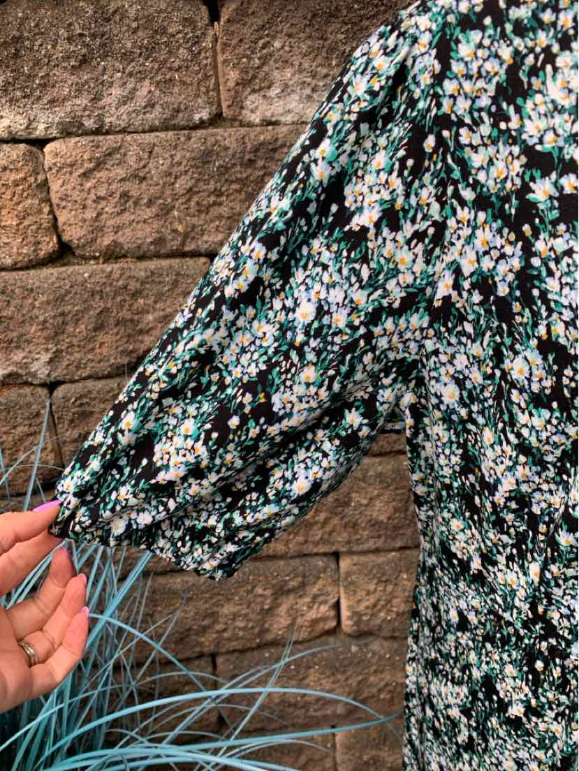 Black long-sleeve dress with small white, blue, and green floral print and elastic cuffs.