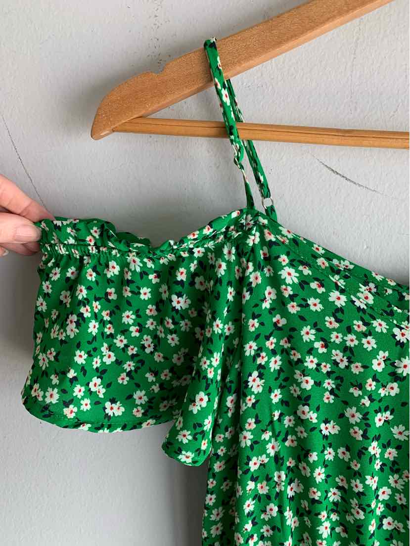 Green floral crop top with puff sleeves and adjustable spaghetti strap.