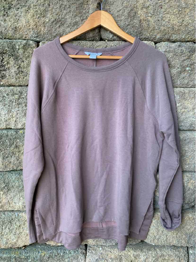 Mauve long-sleeve crew neck sweatshirt with relaxed fit and ribbed cuffs hanging on wooden hanger.