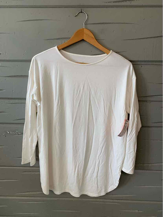 White long-sleeve crew neck shirt with relaxed fit and tag on sleeve hanging on wooden hanger.