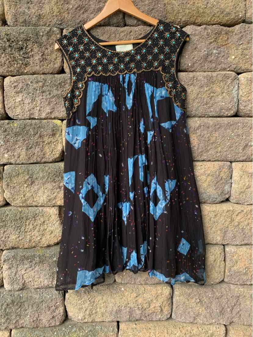 Black sleeveless dress with blue geometric patterns and beaded neckline on wooden hanger.