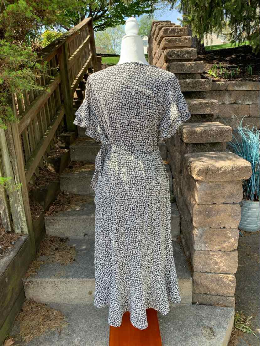 Black and white floral maxi dress with short sleeves and cinched waist on mannequin outdoors.