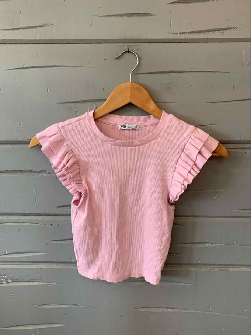 Light pink short-sleeve knit top with ribbed texture and ruffled sleeves on wooden hanger.