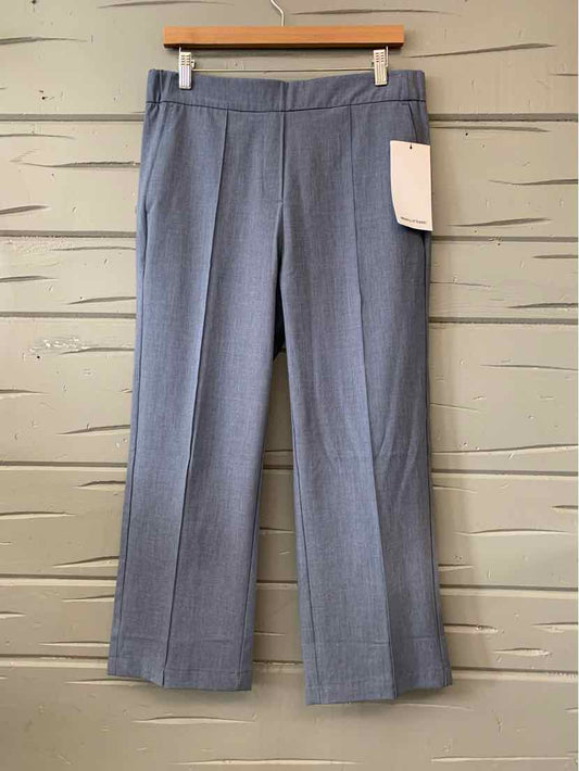 Light blue tailored dress pants with front crease and belt loops hanging on wooden hanger.