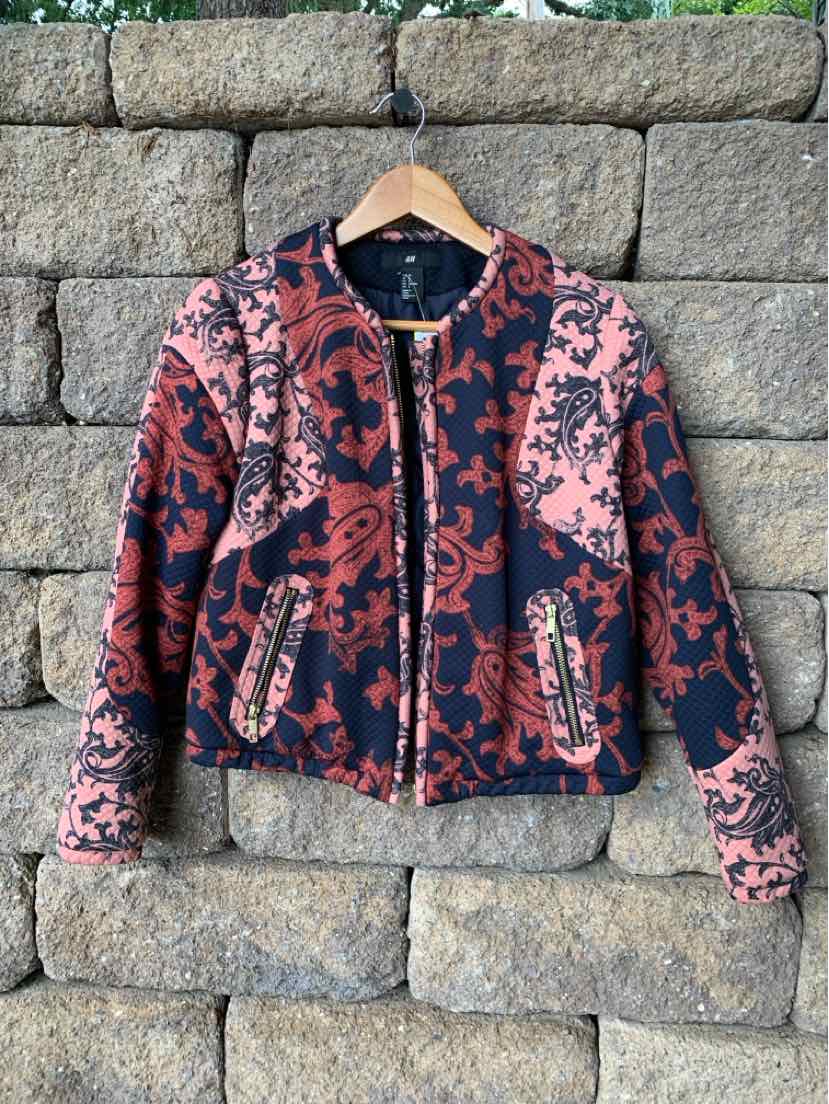 Pink and black paisley-patterned zip-up jacket with a round collar and front pockets.