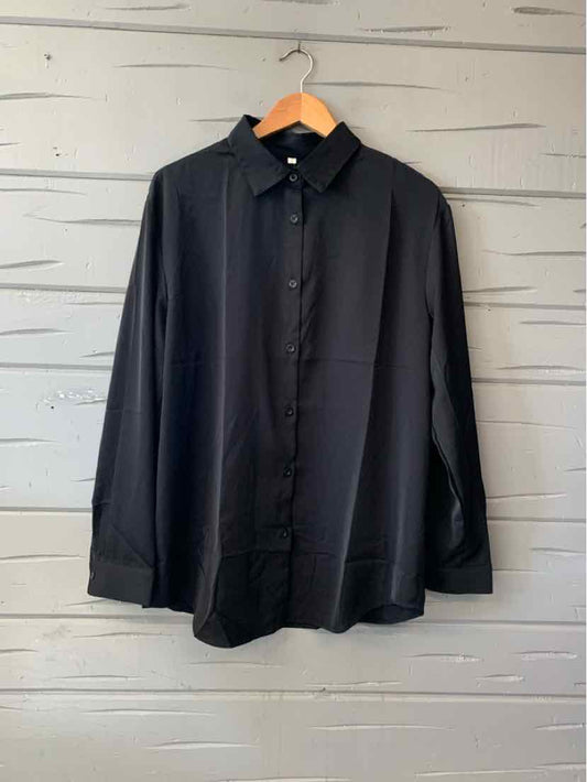 Solid black long-sleeve button-up shirt with a pointed collar and chest pocket, hanging on a wooden hanger.