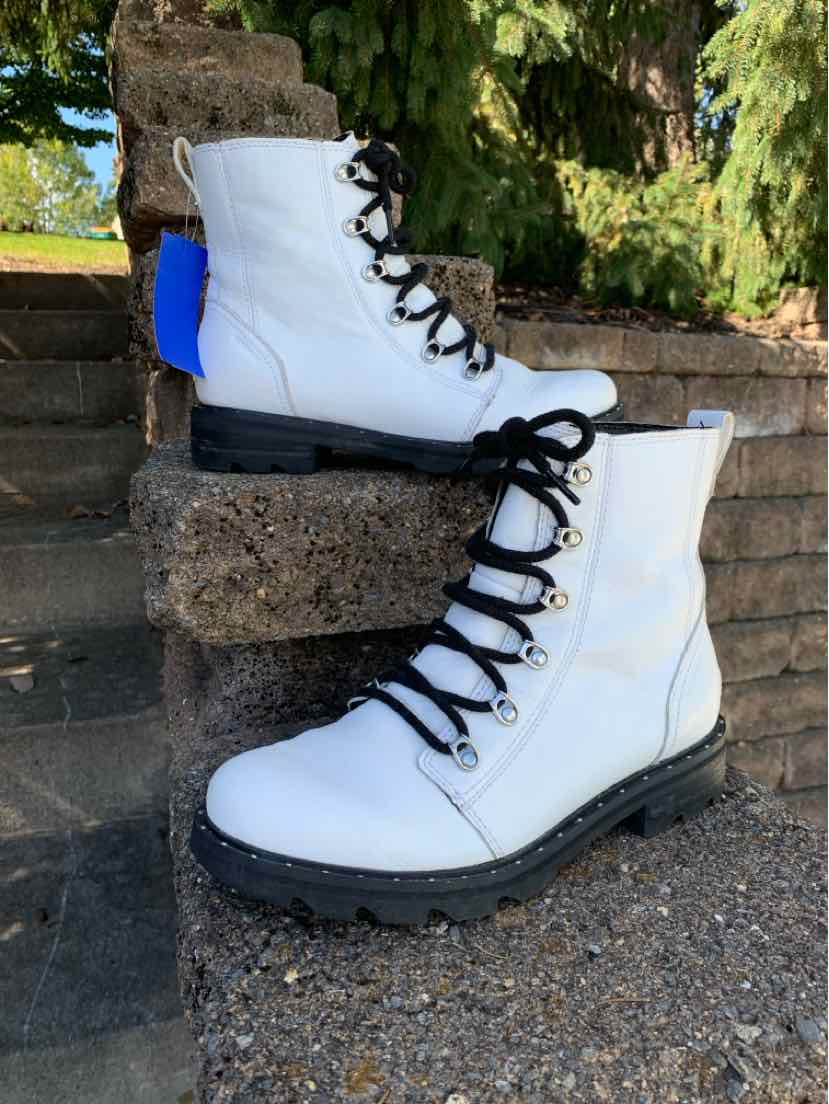 White leather Sorel lace-up boots with black laces, metal eyelets, and thick lug soles.