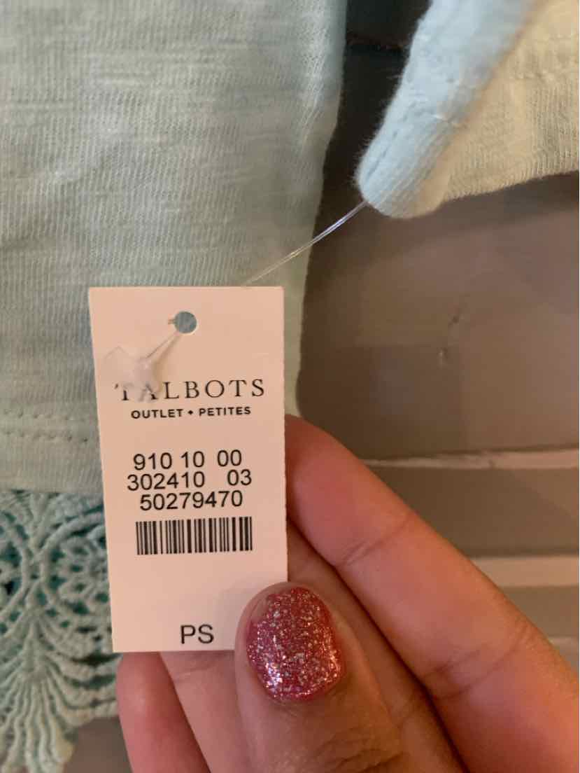 Close-up of Talbots clothing tag on light aqua fabric with textured knit pattern and speckled nail polish on fingers.