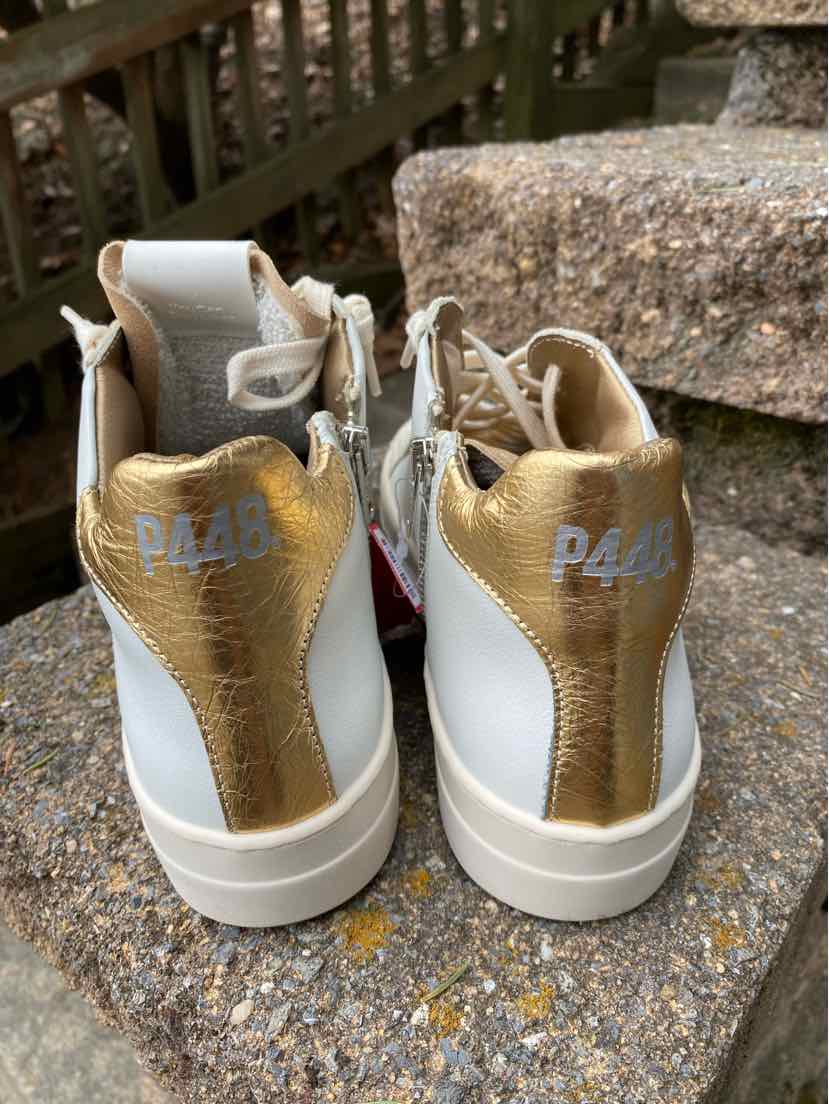 White sneakers with gold metallic heel accents and gray "P448" branding on the back, size 39.