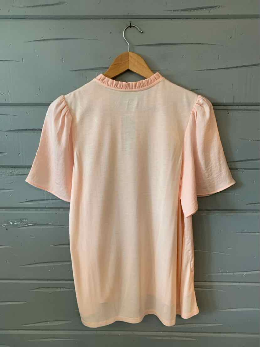 Light peach short-sleeve blouse with gathered detailing on shoulders and a round neckline on wooden hanger.