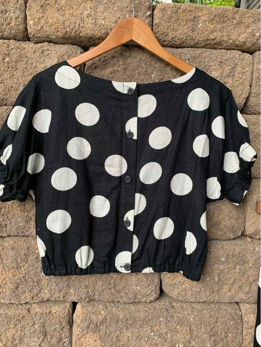 Black cropped blouse with large white polka dots, puff sleeves, and button front closure.
