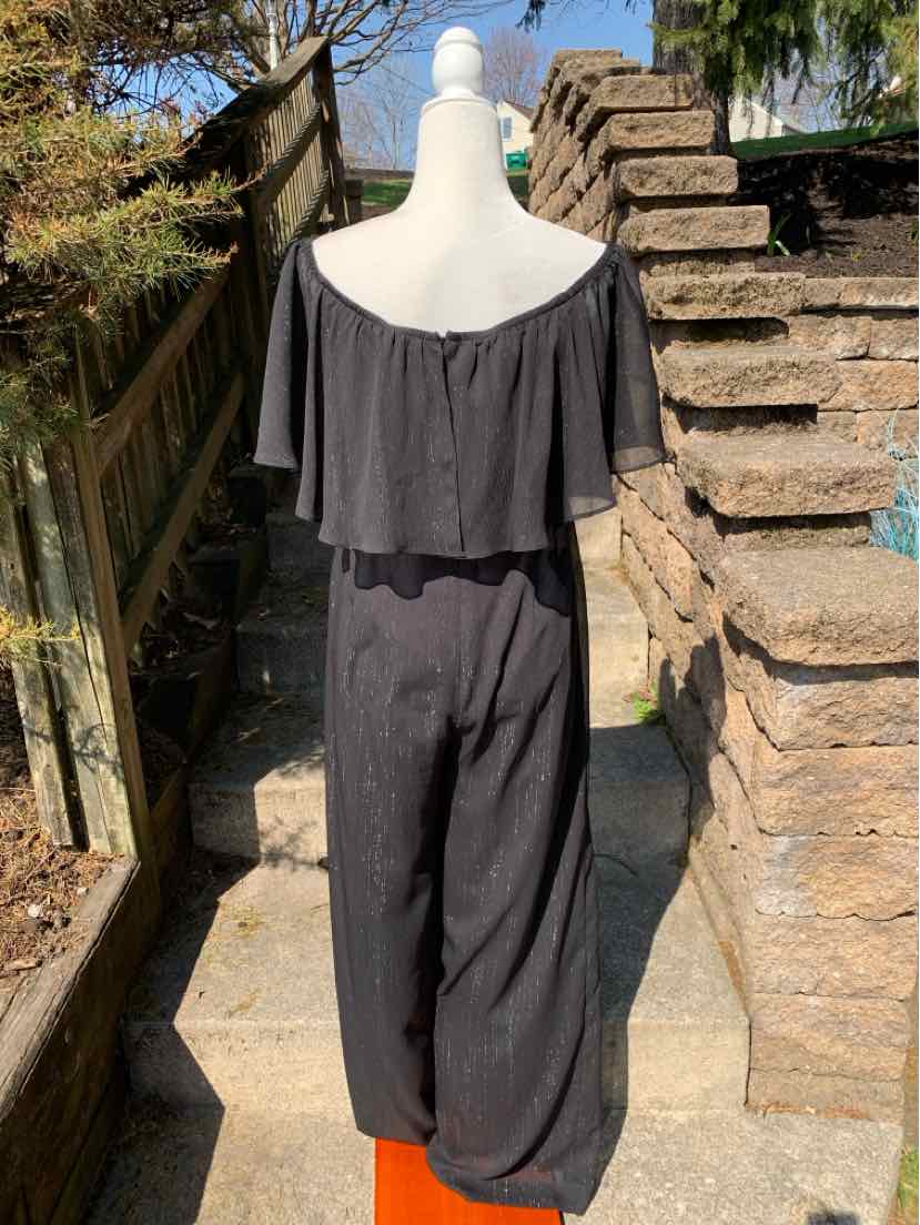 Black off-shoulder jumpsuit with loose wide legs and ruffle neckline detail.