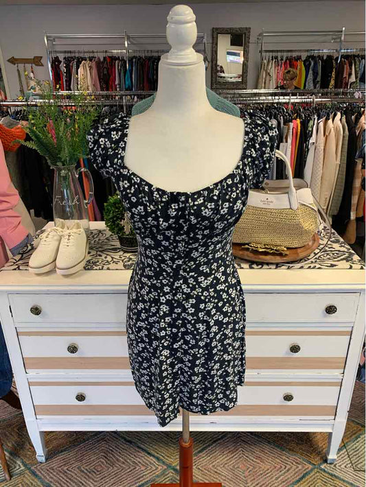Black floral print dress with short puff sleeves and ruched bodice on mannequin.