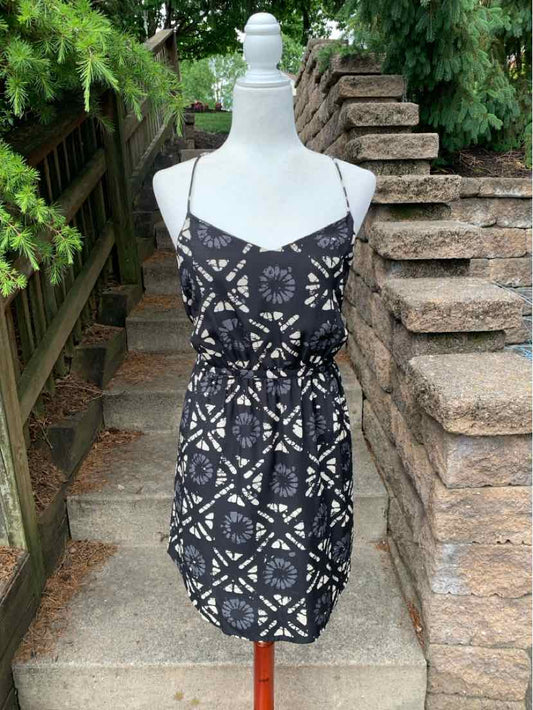 Black sleeveless dress with white geometric floral pattern and adjustable thin straps.