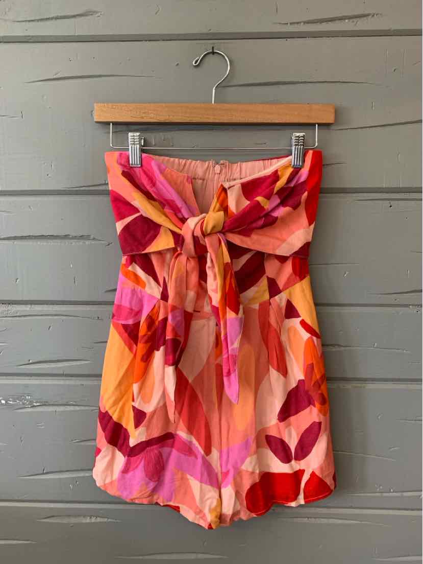Sleeveless multi-color romper with pink, orange, and red abstract pattern and front tie waist.