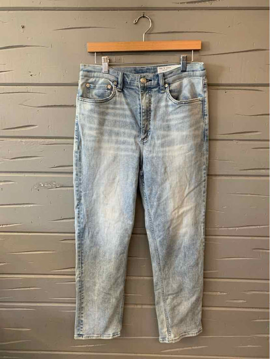 Light blue faded denim jeans with five-pocket design and button fly, hanging on wooden hanger.