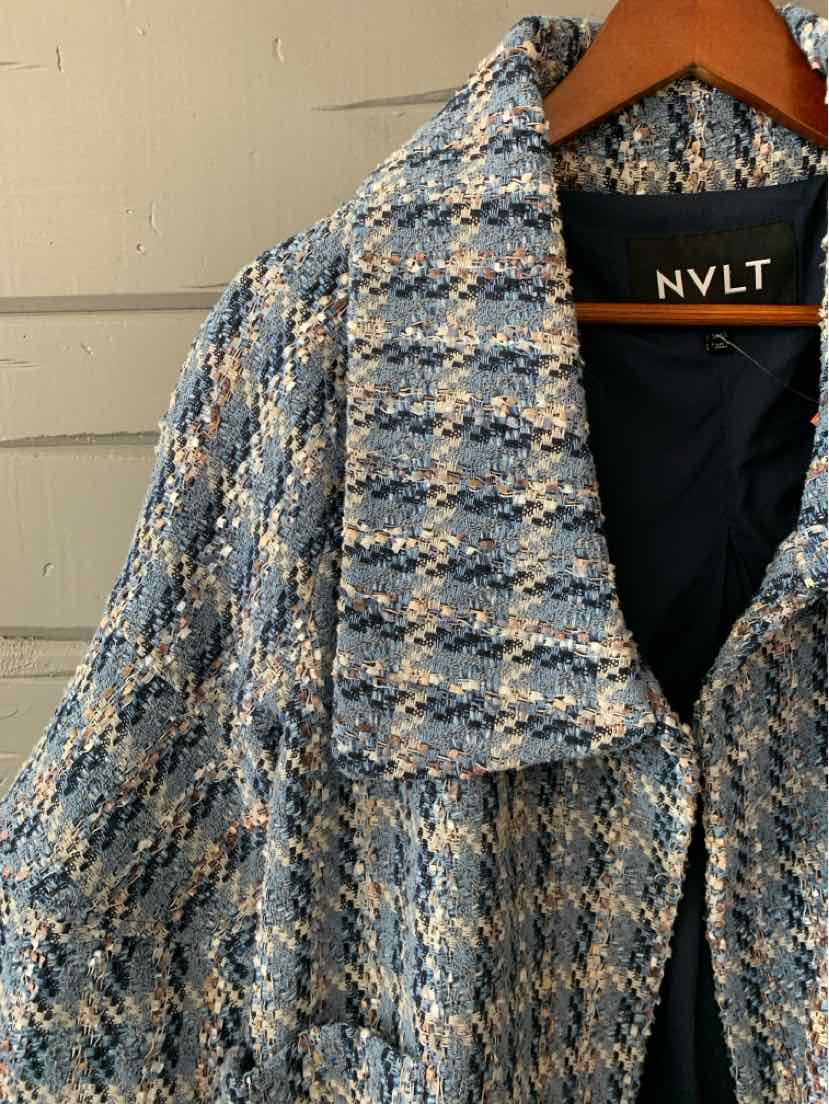 Blue and beige tweed coat with wide collar and black inner lining hanging on wooden hanger.