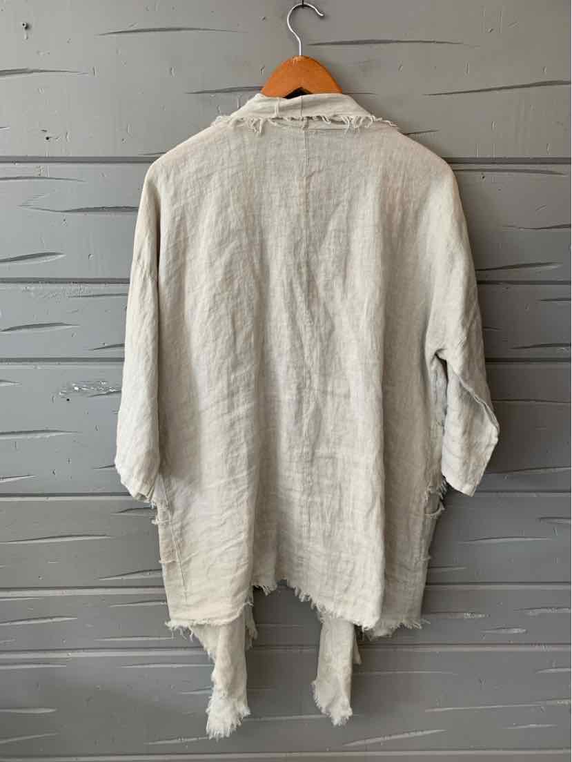 Light beige linen long-sleeve shirt with frayed edges and relaxed fit hanging on wooden hanger.
