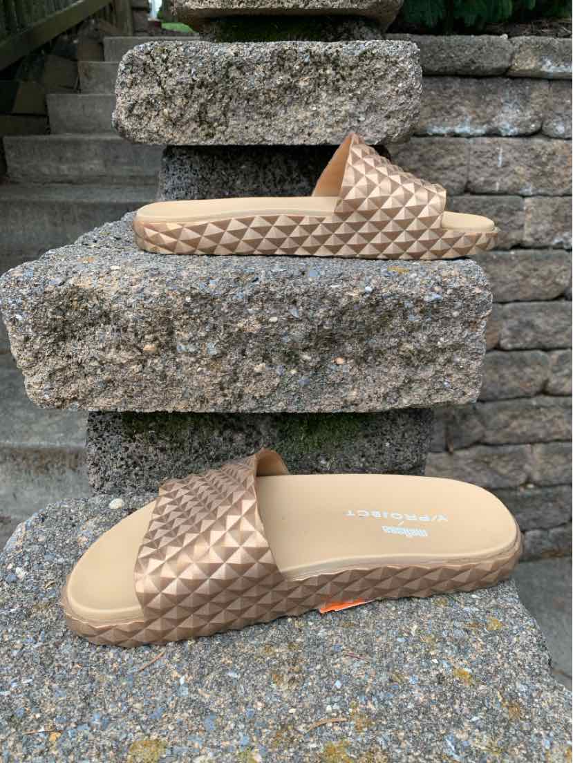 Metallic bronze slide sandal with woven textured strap and cushioned sole.