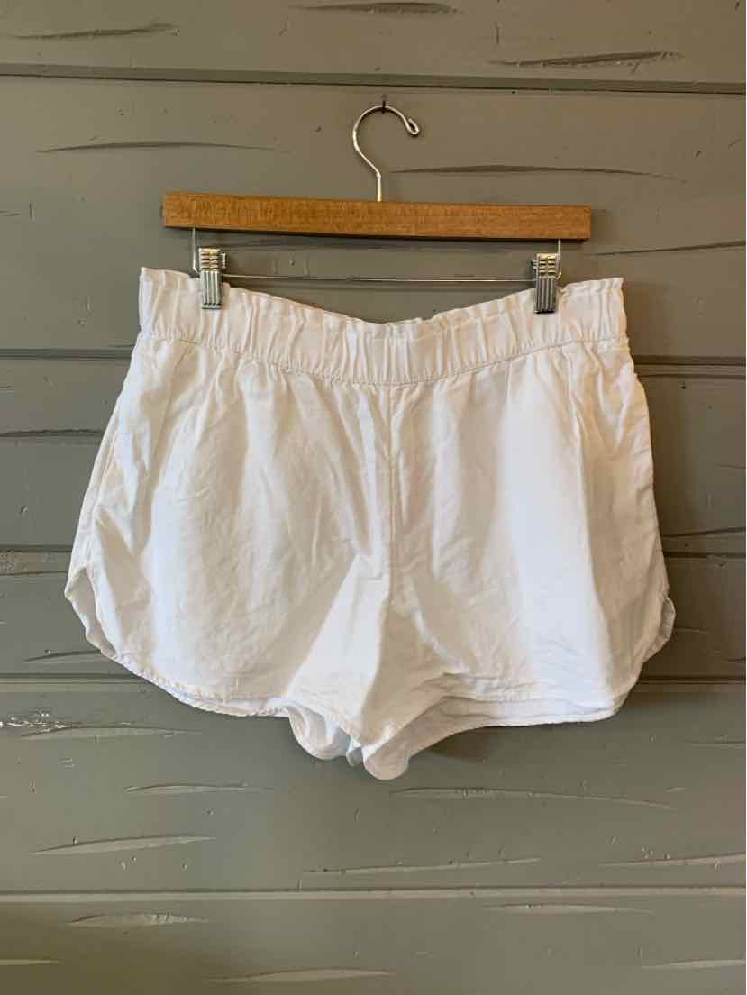 White elastic waist casual shorts with curved hem and lightweight fabric hanging on wooden hanger.