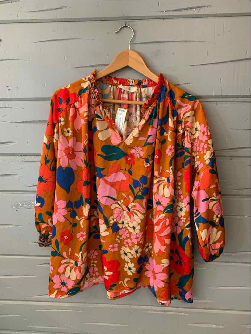 Rust-orange floral blouse with pink, blue, and green flower patterns, V-neck, and loose fit.