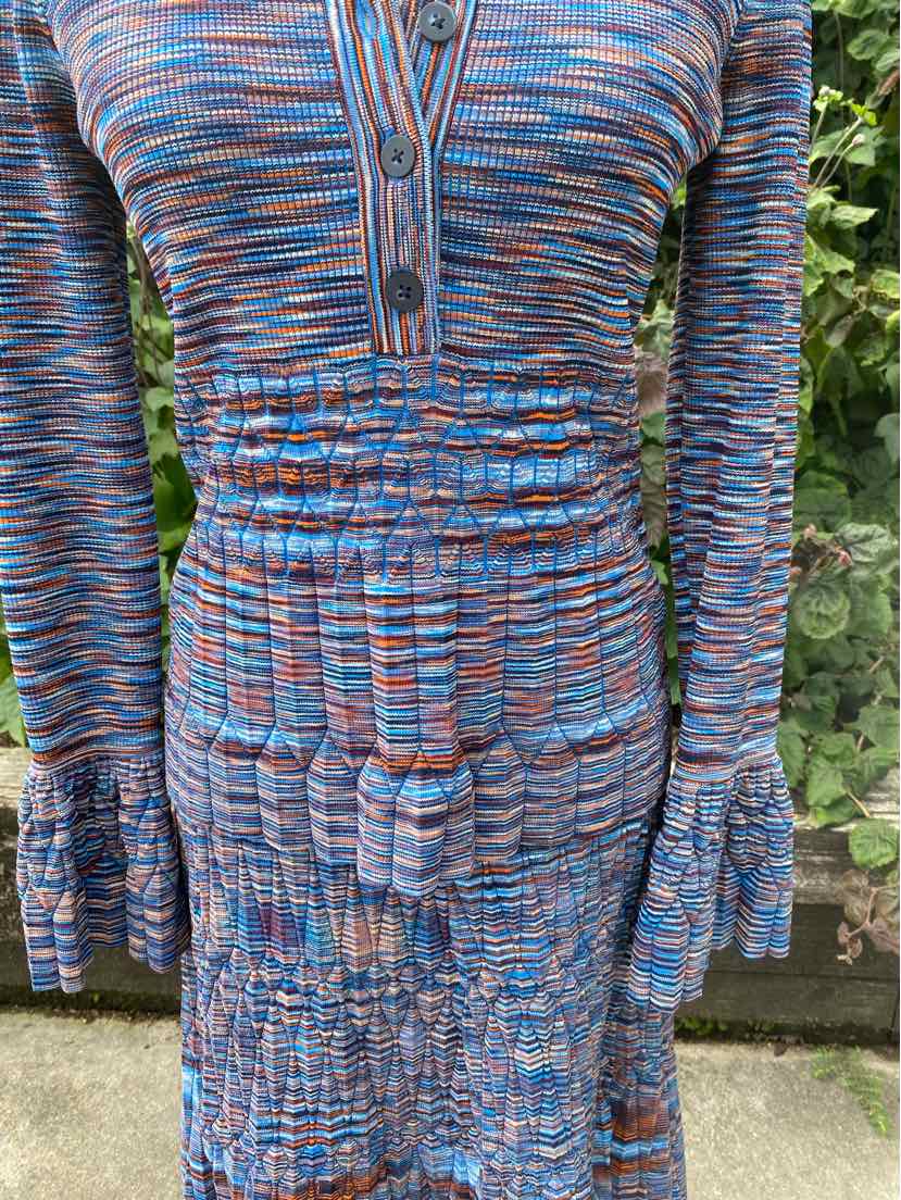 Long-sleeve fitted dress with blue, orange, and navy space-dyed pattern, buttoned V-neck, and ruched waist.
