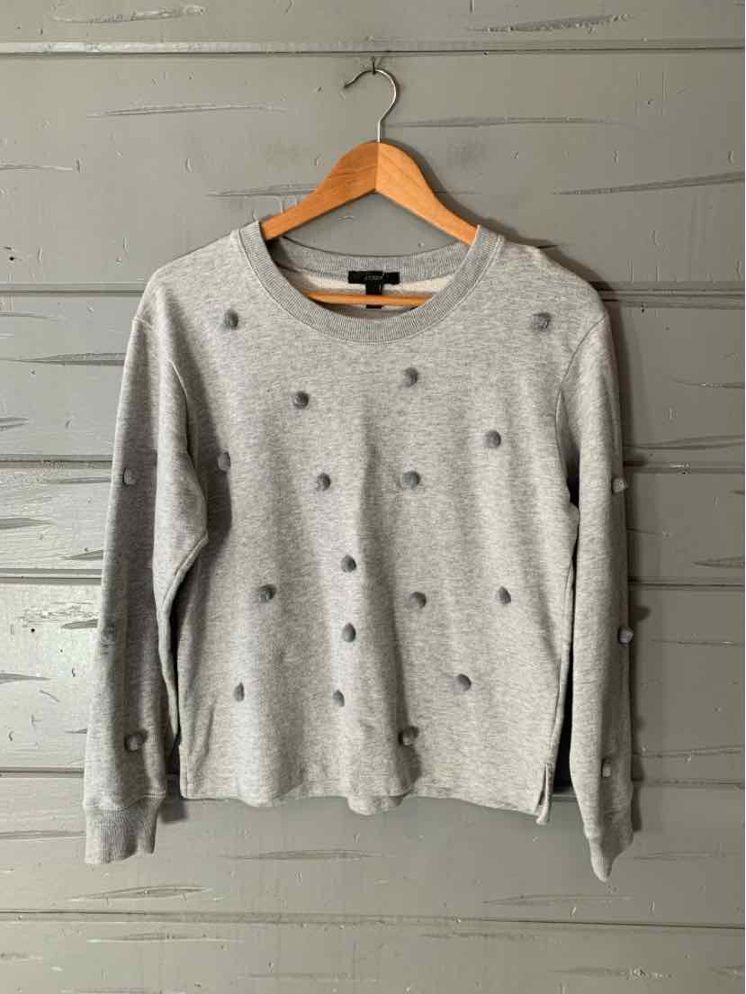 Women’s light gray J.Crew sweater with a crew neck and scattered dark embellishments, hanging on a wooden hanger.