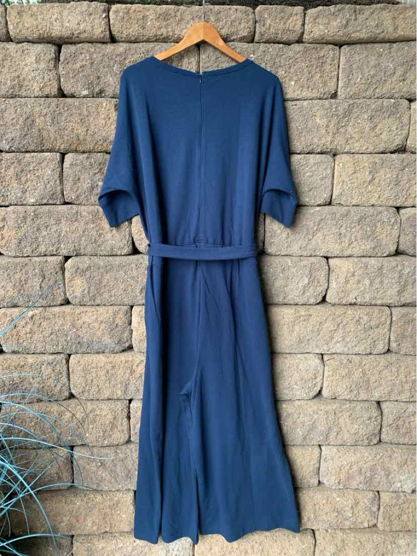 Navy blue wide-leg lounge jumpsuit with short sleeves and waist tie hanging on wooden hanger.