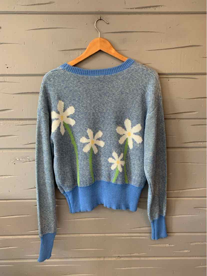 Blue knit sweater with white floral patterns, ribbed cuffs and hem, relaxed fit.