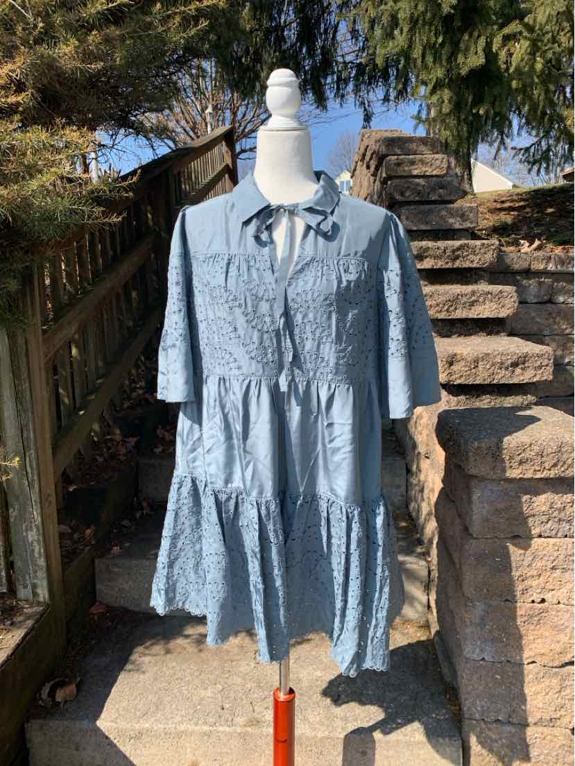 Light blue eyelet dress with tiered skirt, half sleeves, and front tie neckline on mannequin outdoors.
