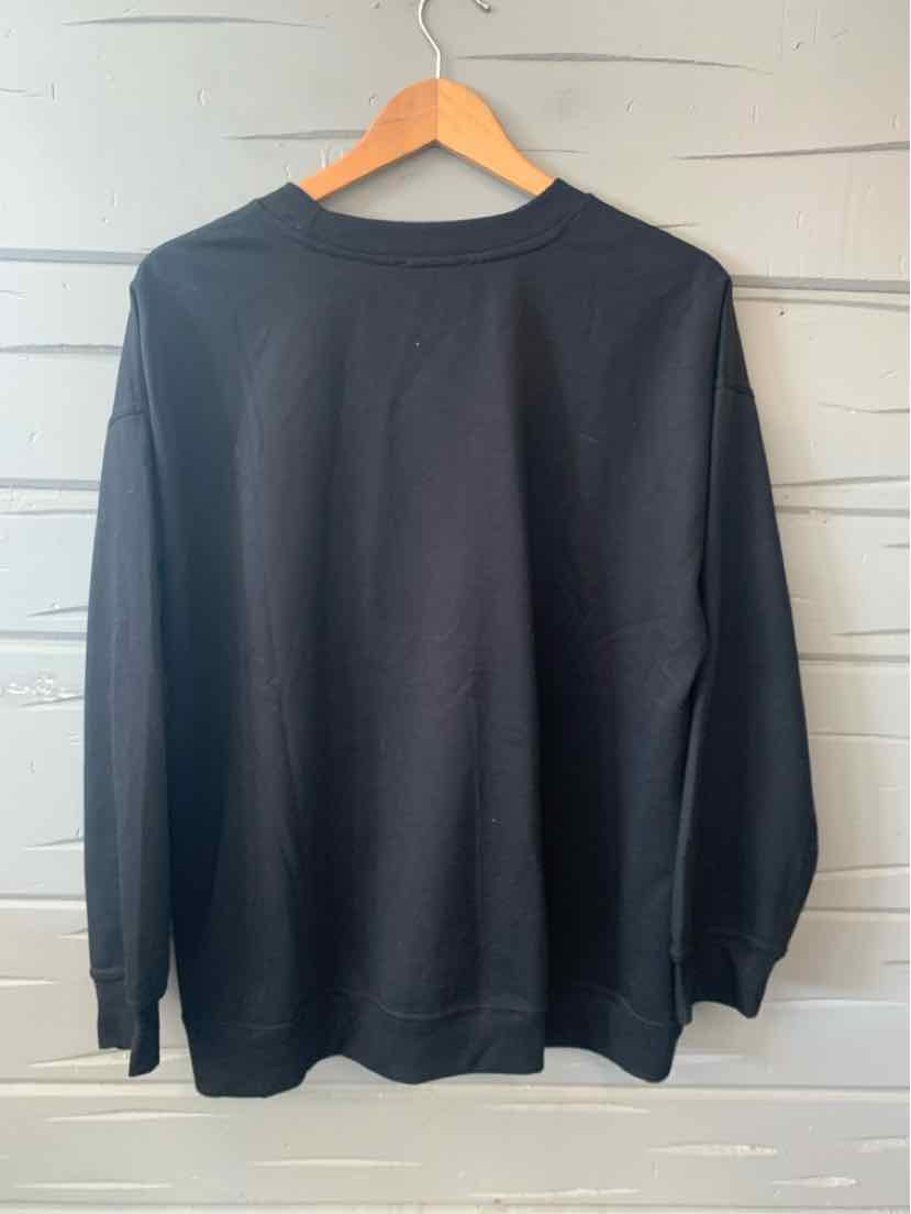 Black long-sleeve crewneck sweatshirt with ribbed cuffs and hem hanging on wooden hanger.