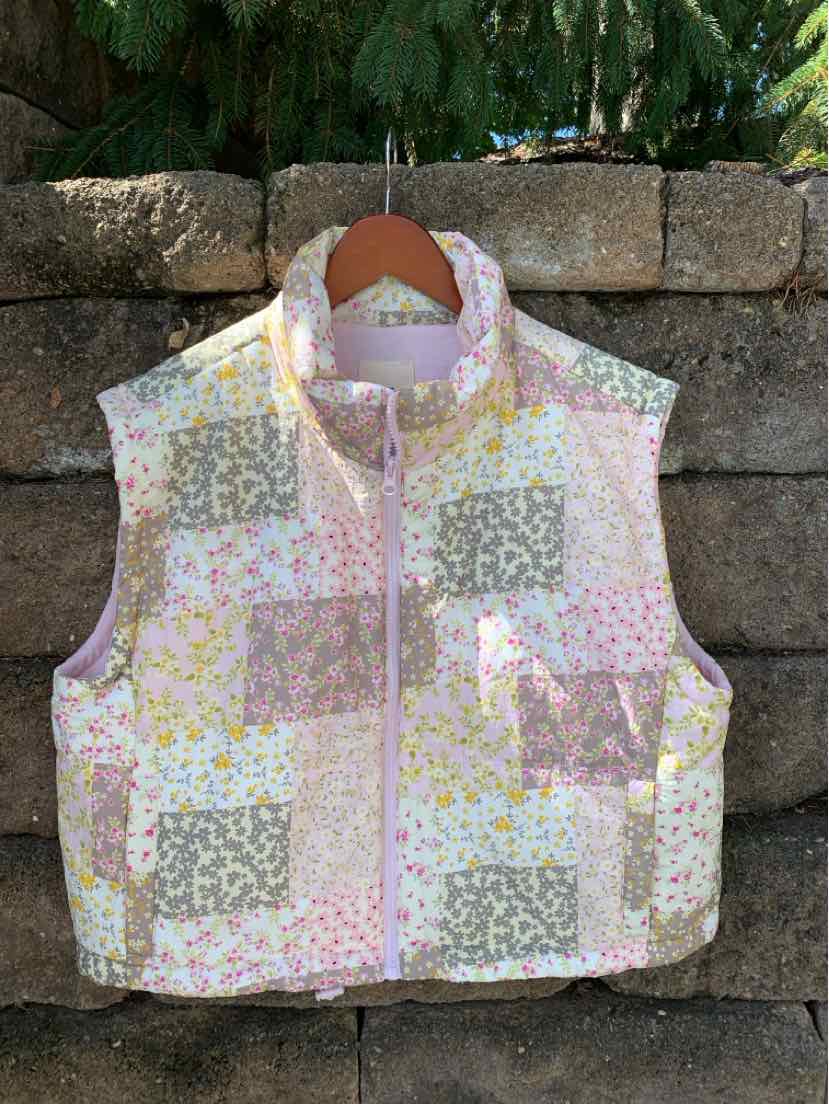 Sleeveless cropped vest with patchwork floral patterns in pink, yellow, and gray, zip front closure.