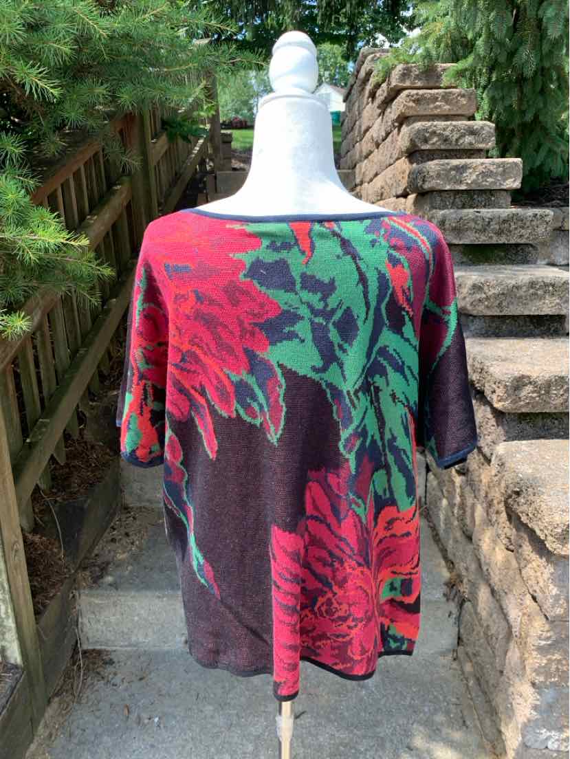 Loose-fitting burgundy sweater with large green and red floral print, wide neckline, and long sleeves.