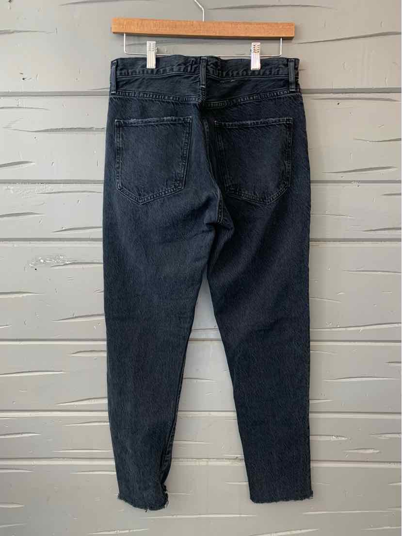 Black high-waisted denim jeans with back pockets and tapered legs hanging on a wooden hanger.