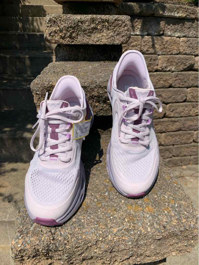 Light pink women's athletic sneakers with mesh upper, cushioned soles, and lace-up closure.