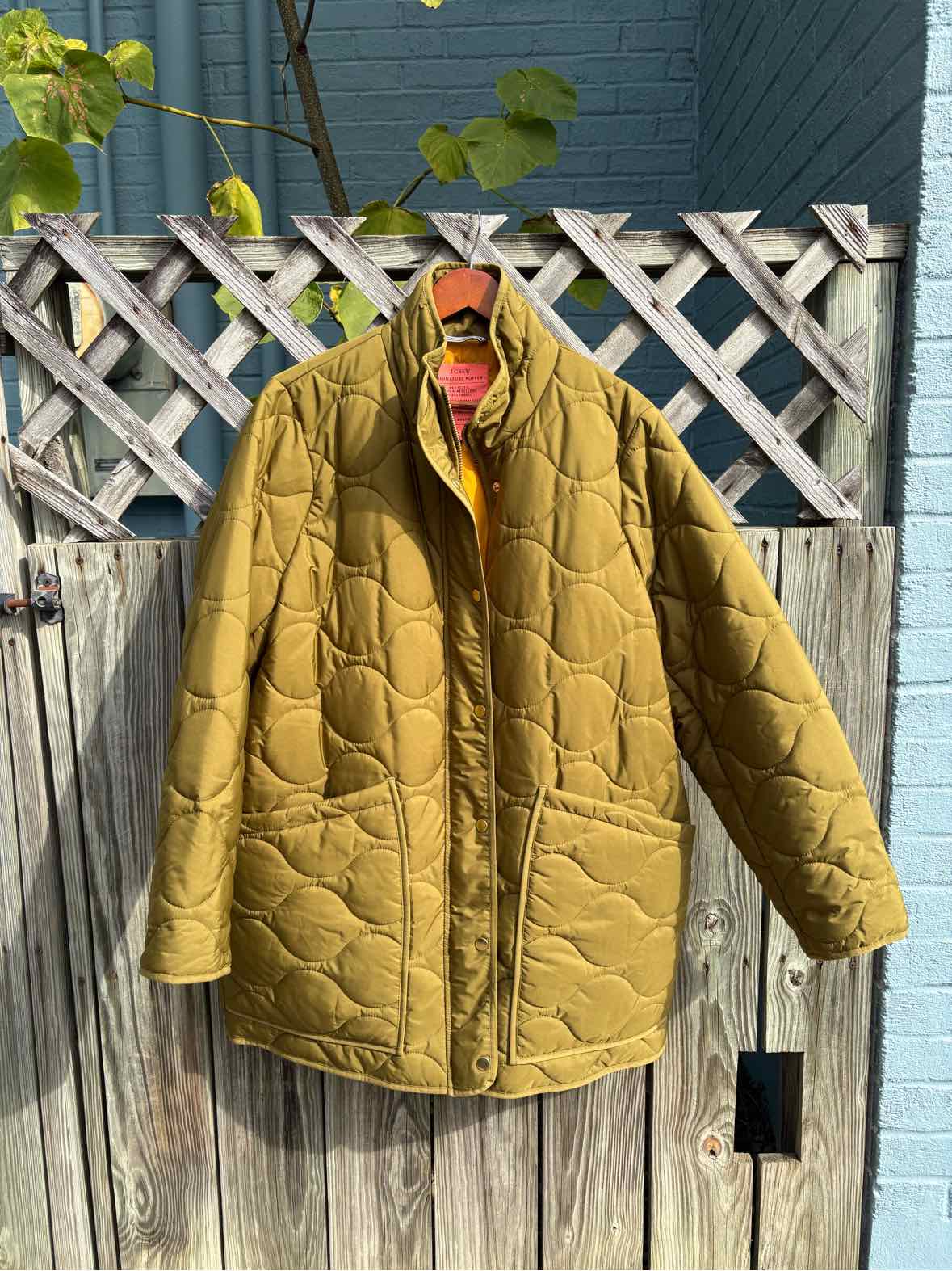 Olive green J.Crew quilted coat with a corduroy collar, snap-front closure, and patch pockets.
